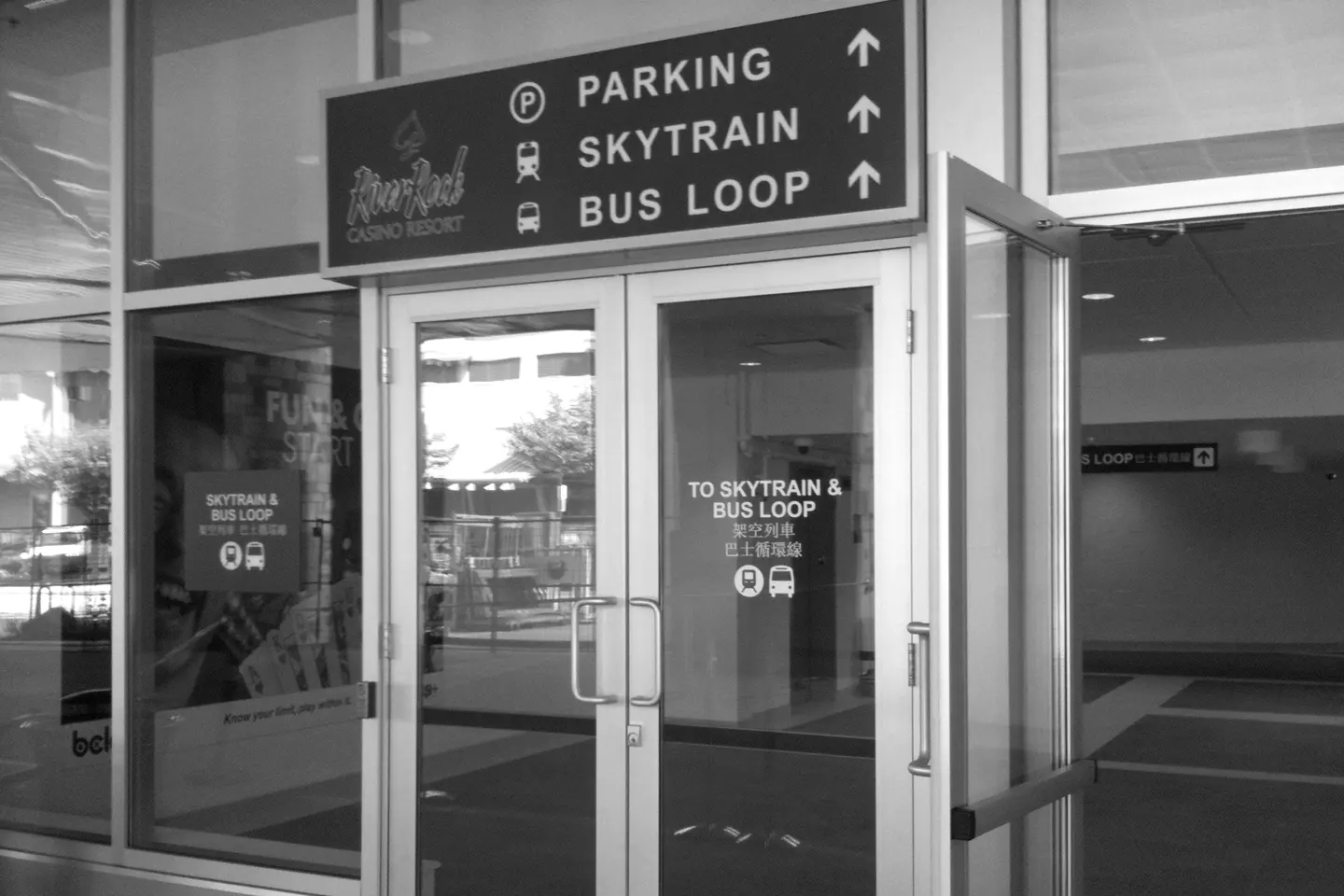 Glass doors of River Rock under a direction sign